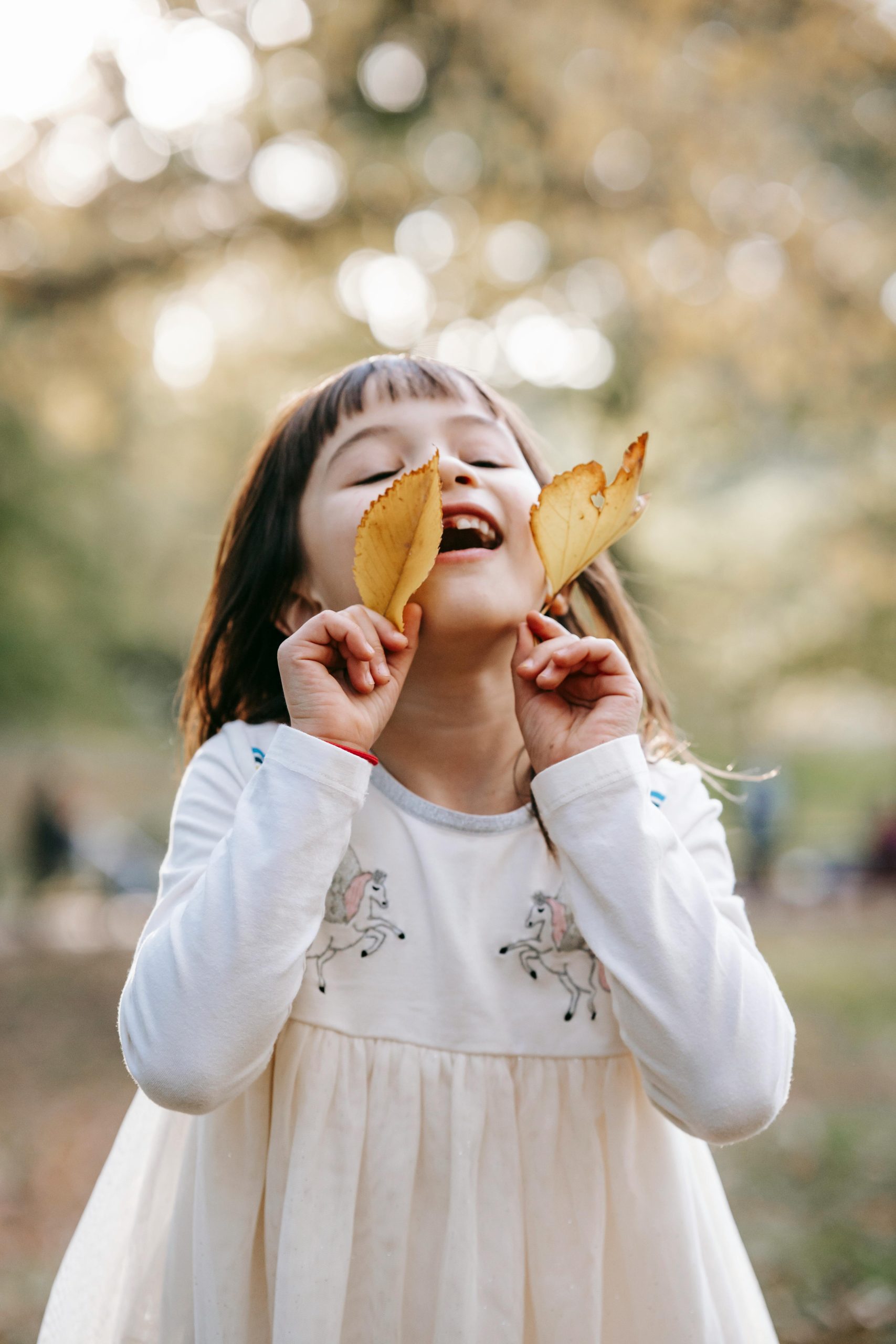 A child picks up some leaves and plays with them at Little Big People Early Learning.